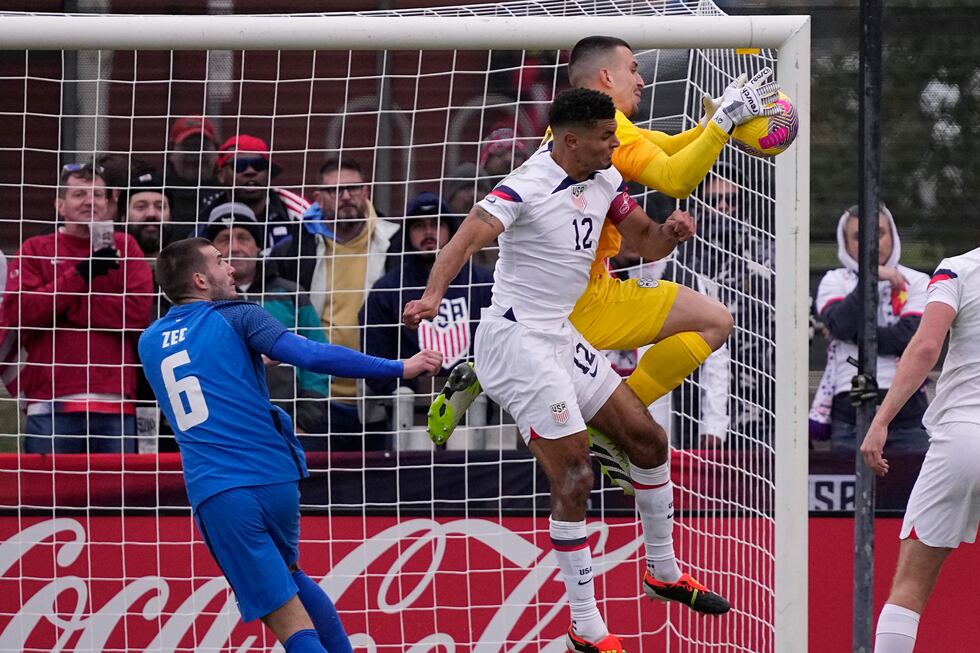 Slovenia goalkeeper Igor Vekic, right, leaps in front of United States defender Miles Robinson...